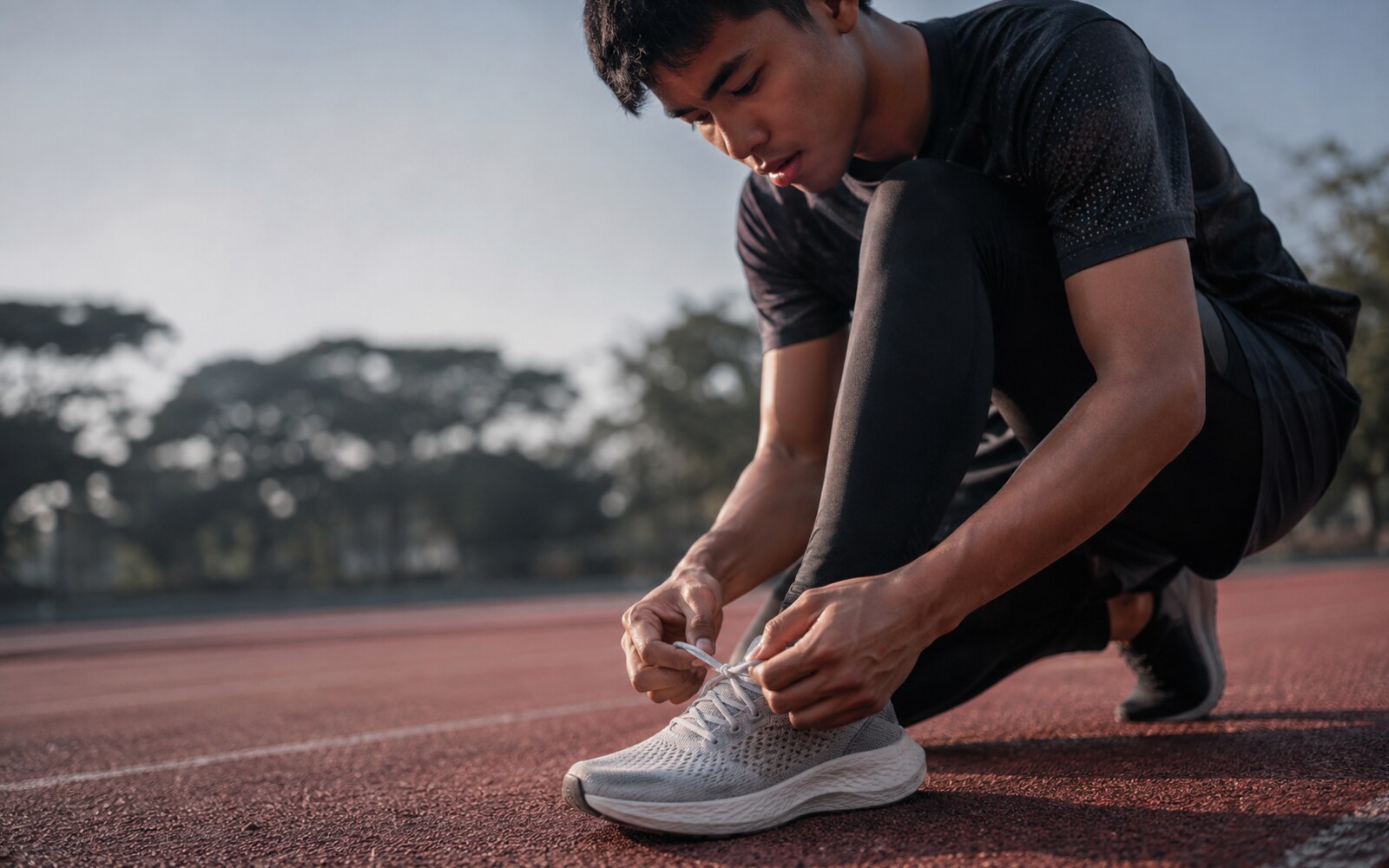 Siluet sepatu lari dengan bantalan stabil dan upper bernapas.
